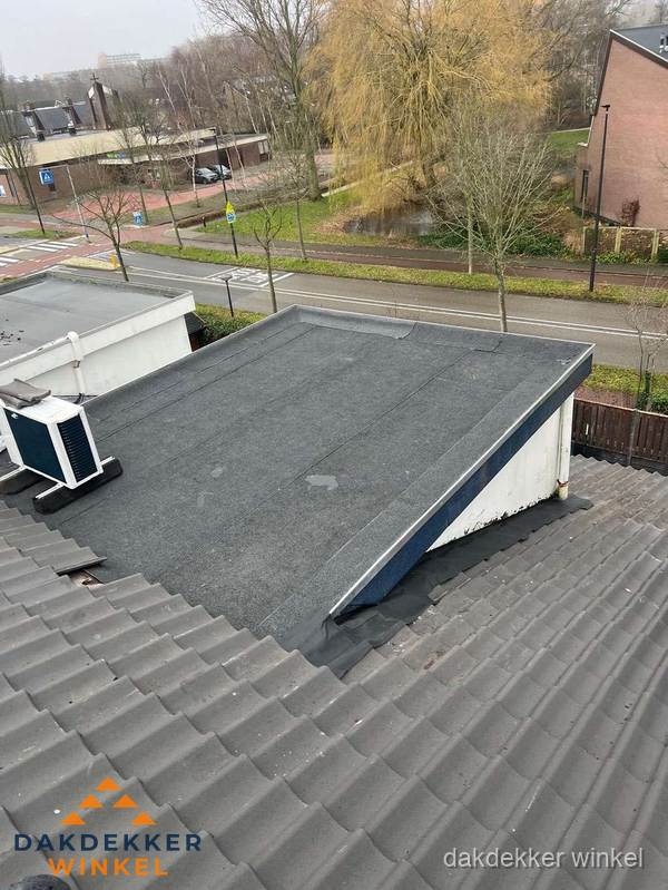 Plat dak met bitumen dakbedekking naast schuin pannendak in Winkel Plat dak met bitumen dakbedekking naast schuin pannendak in Winkel